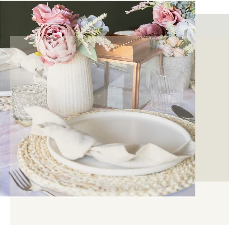 A table set with plates and bowls, flowers in vases.