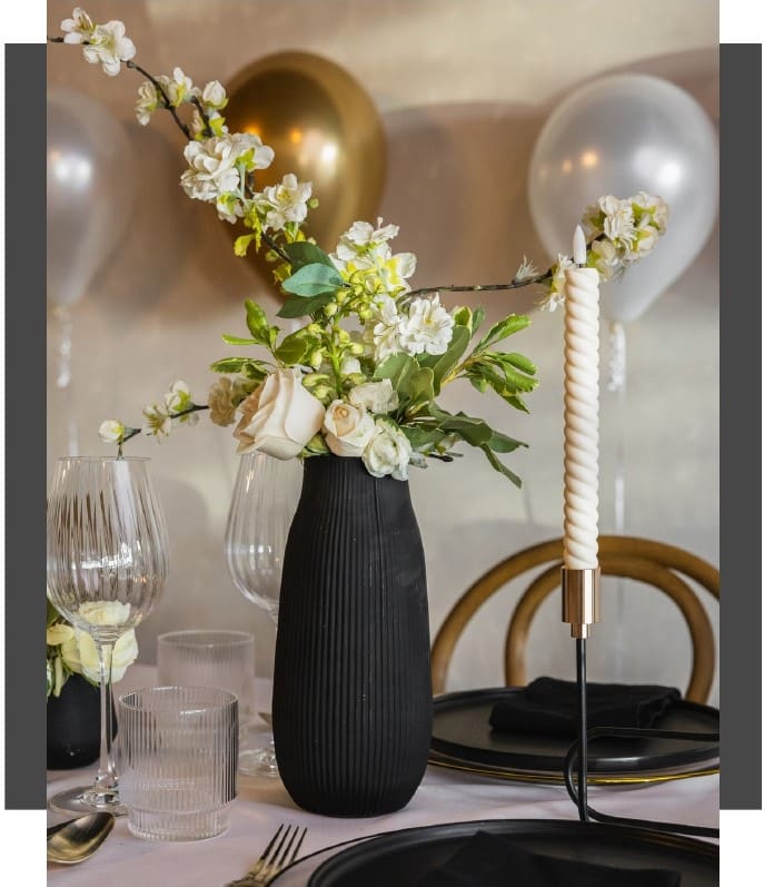 A vase with flowers and balloons on the table.