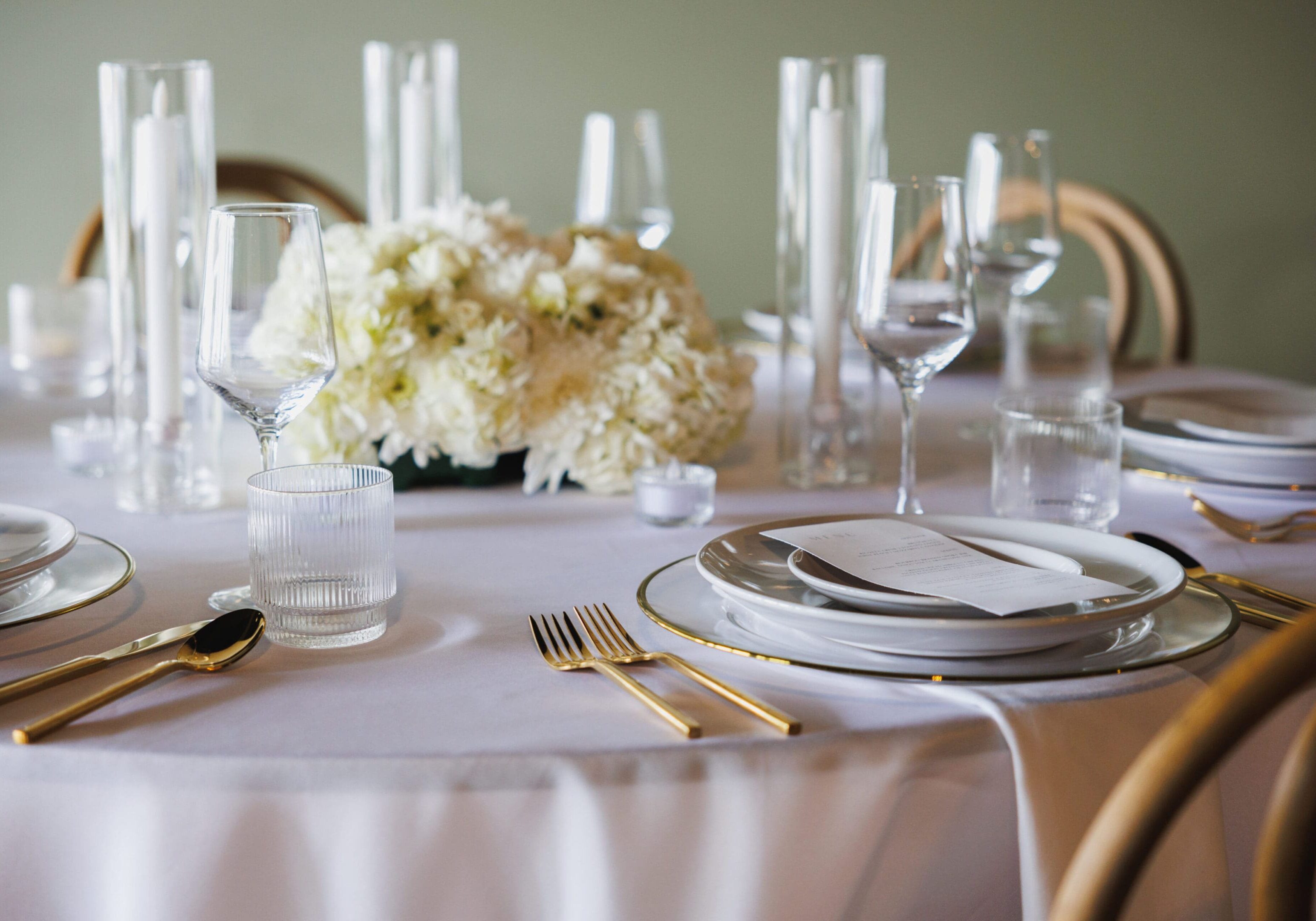 A table set with plates and silverware, glasses and flowers.